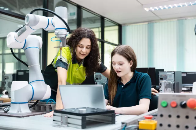 wo female colleagues in a technical lab working together with a laptop to program